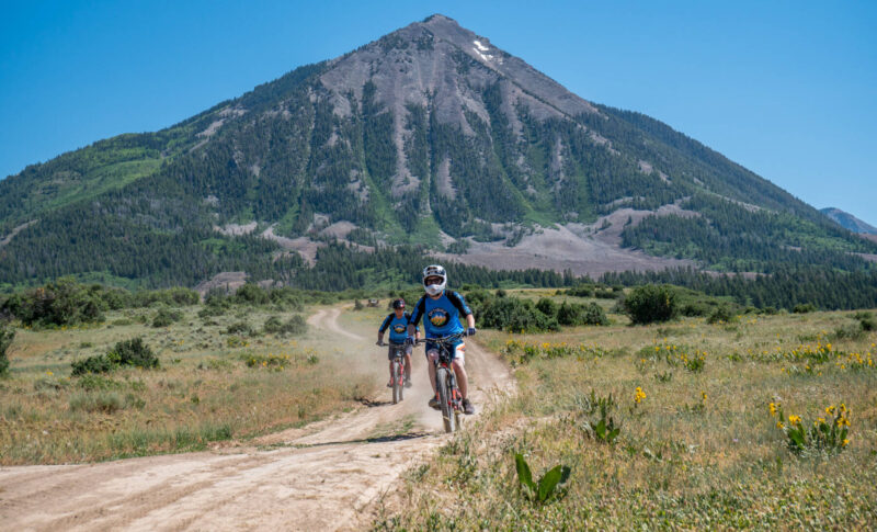 optibike-carbon-duo-mountain 2 electric bikes on trail with mountain background