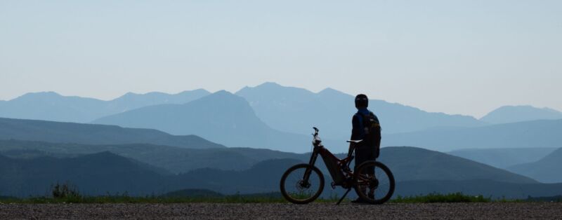 Optibike R22 Everest in the Mountains A silhouette of an Optibike R22 Everest with the rider looking out over jagged mountains in the distance.